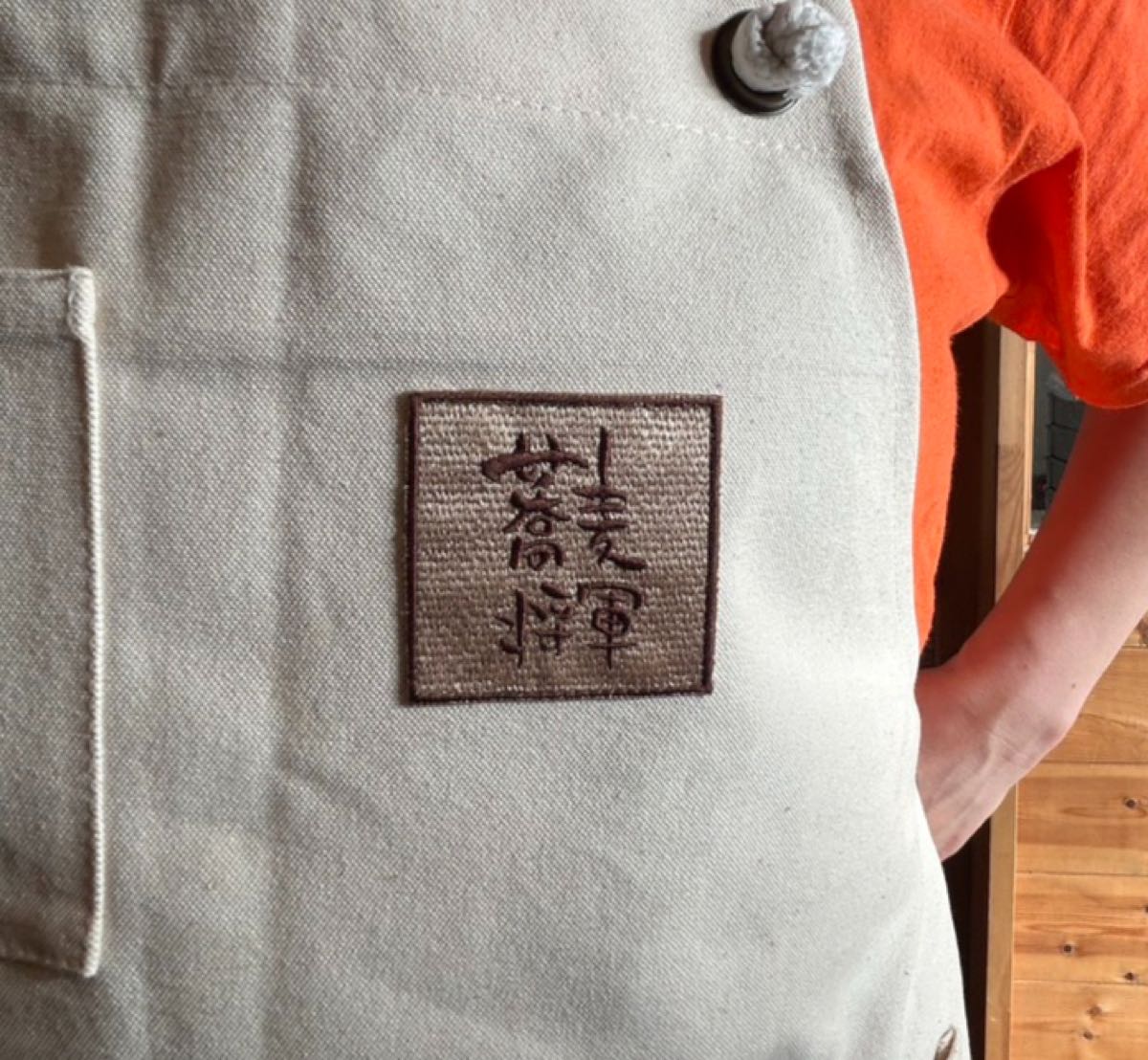 生成りのエプロンに入れた角型の和文字刺繍