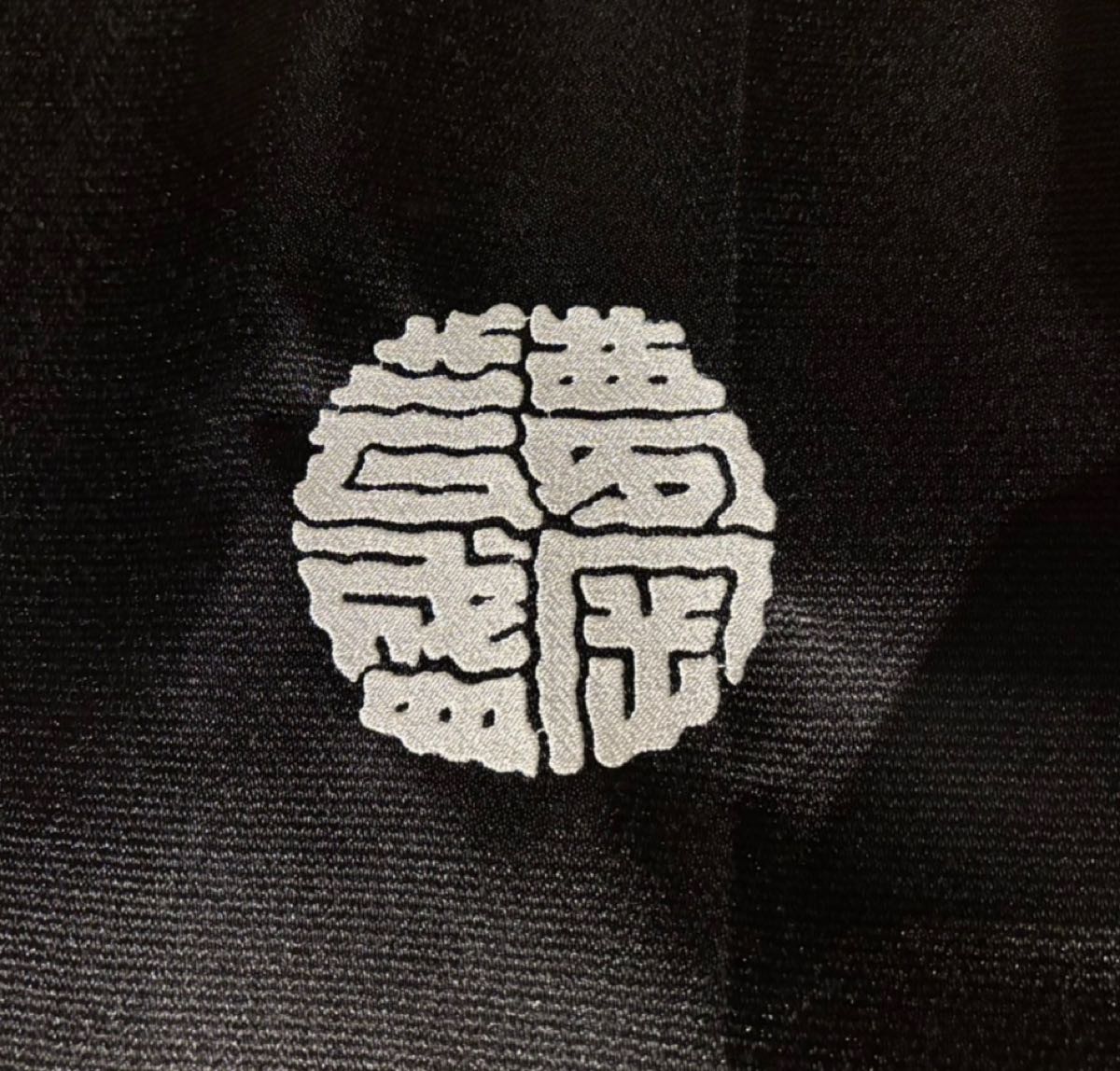 黒い生地に白糸で入れた円形の紋章風刺繍